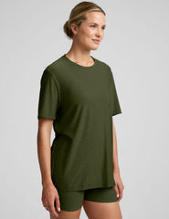 model wearing a green oversized men's t-shirt and biker shorts against a plain background.