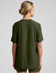 model wearing a green oversized men's t-shirt and biker shorts against a plain background.