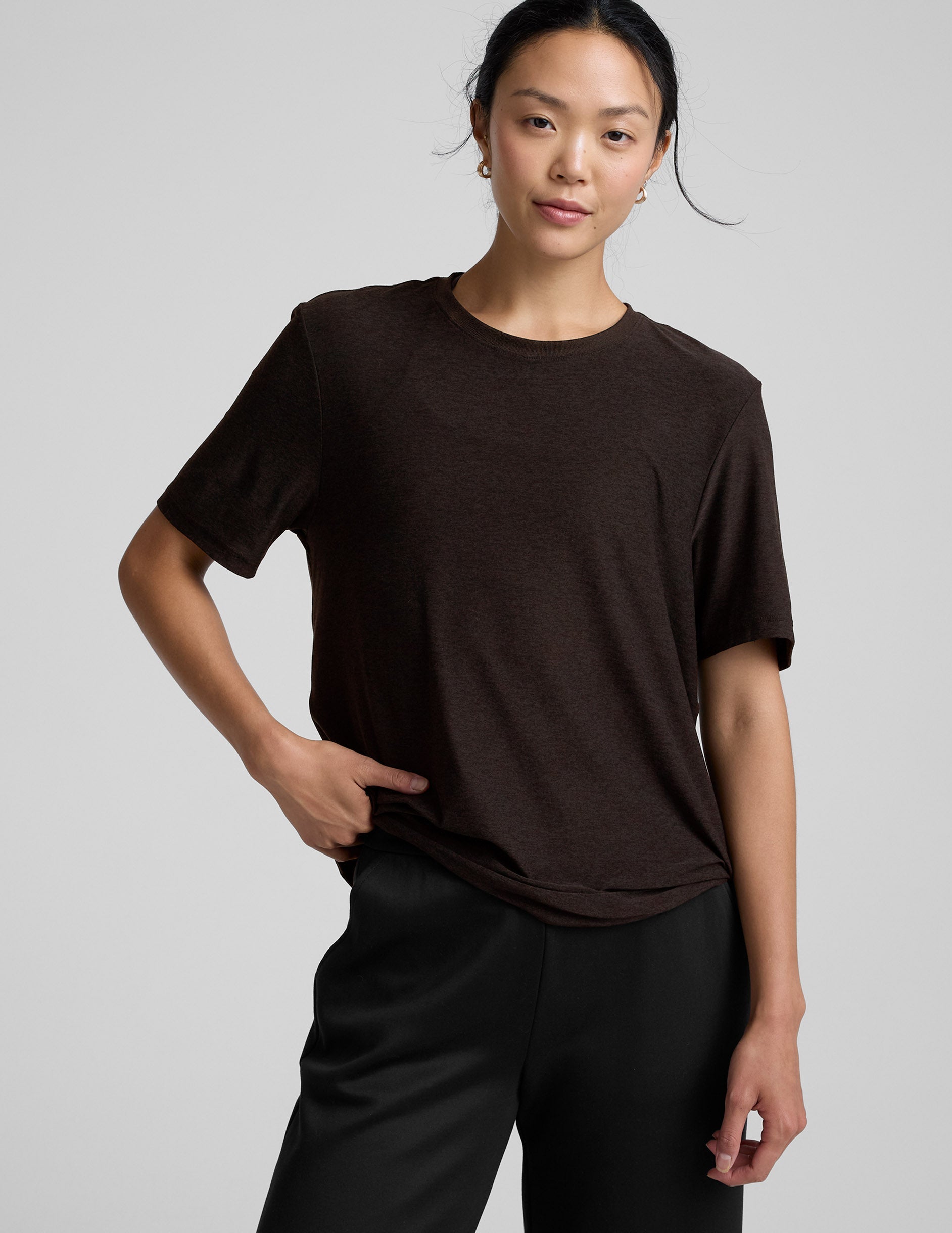 model wearing a brown t-shirt and pants on a light gray background.