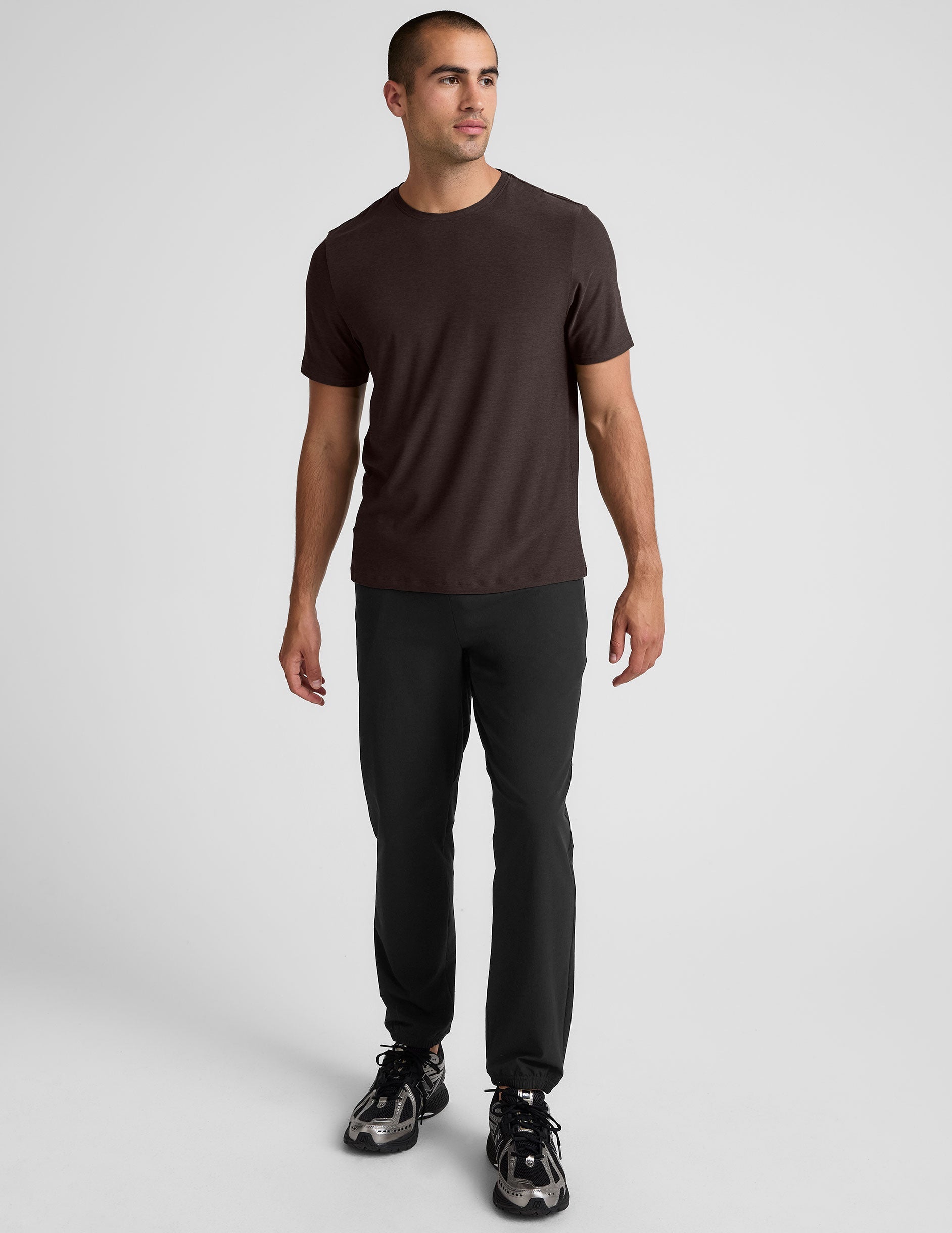 model wearing a brown men's short sleeve t-shirt against a gray background.