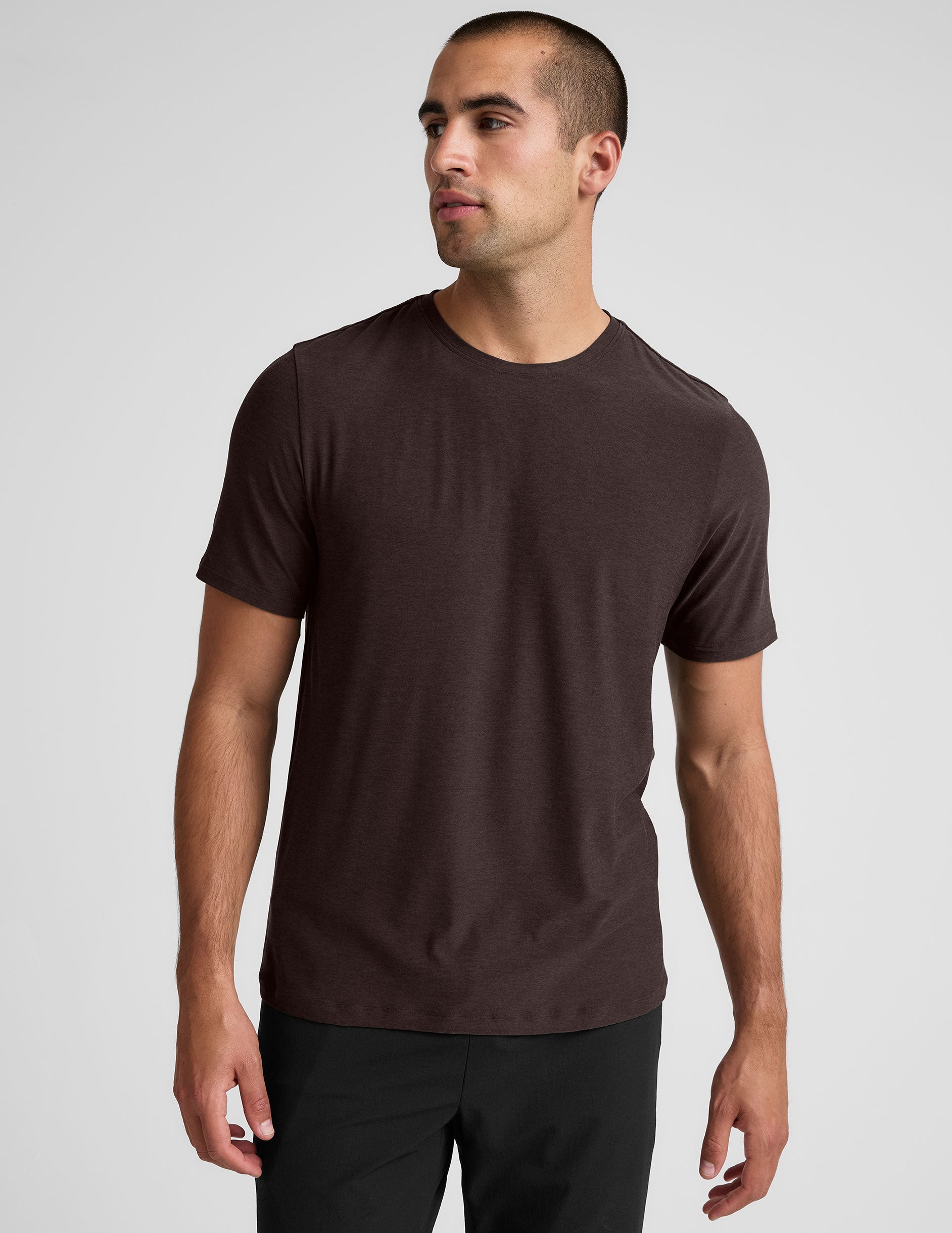 model wearing a brown men's short sleeve t-shirt against a gray background.
