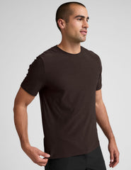 model wearing a brown men's short sleeve t-shirt against a gray background.