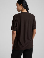 model wearing a brown t-shirt and pants on a light gray background.