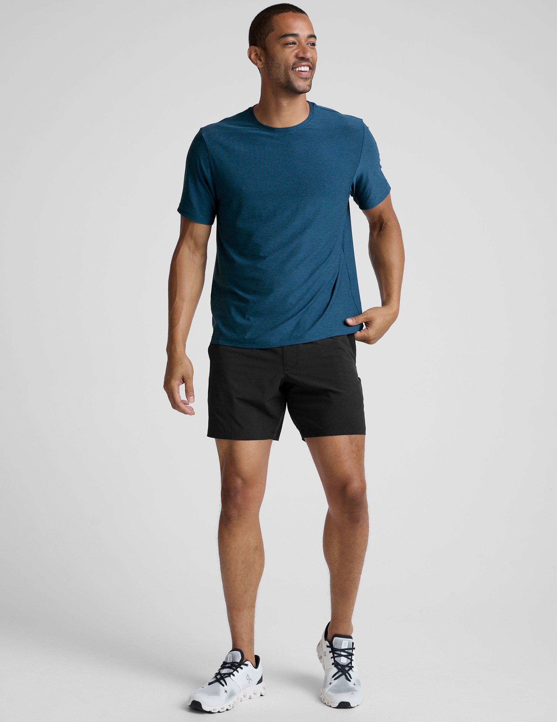 man wearing a blue t-shirt and black shorts against a plain background.