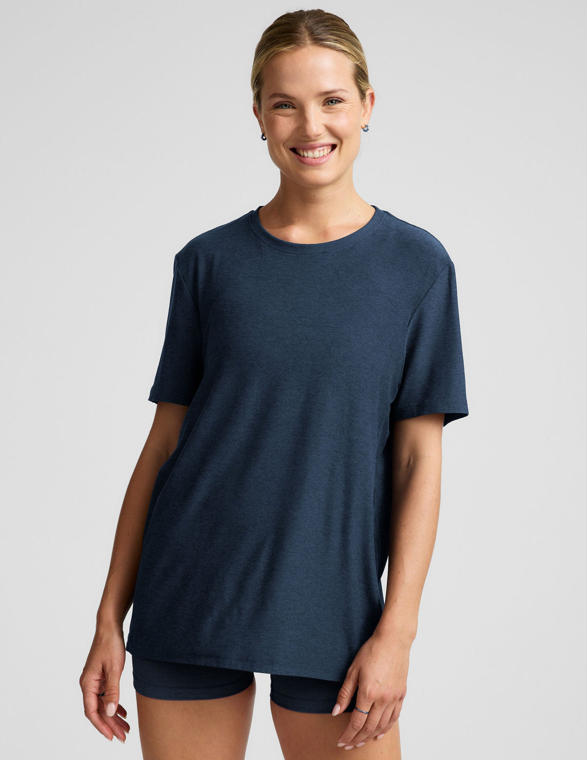 model wearing a blue oversized men's t-shirt and biker shorts against a plain background.