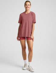 model wearing an oversized men's red t-shirt and shorts on a plain background.