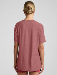 model wearing an oversized men's red t-shirt and shorts on a plain background.