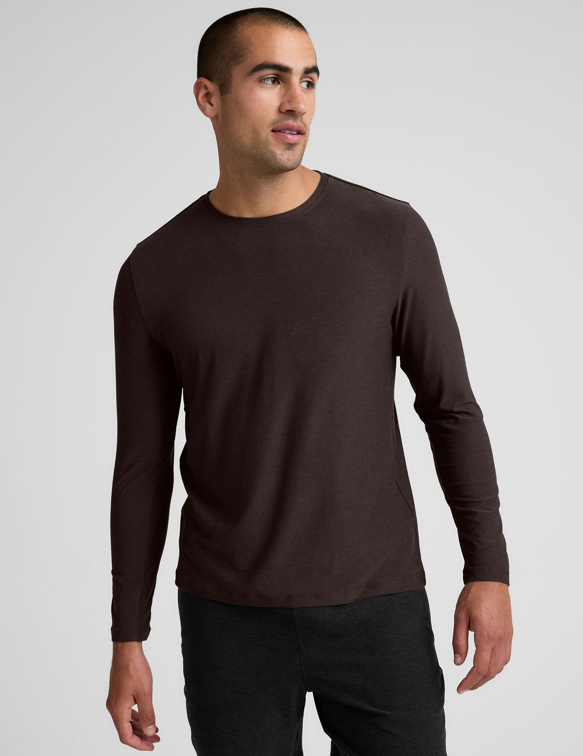 model wearing a brown men's long-sleeve shirt against a gray background.