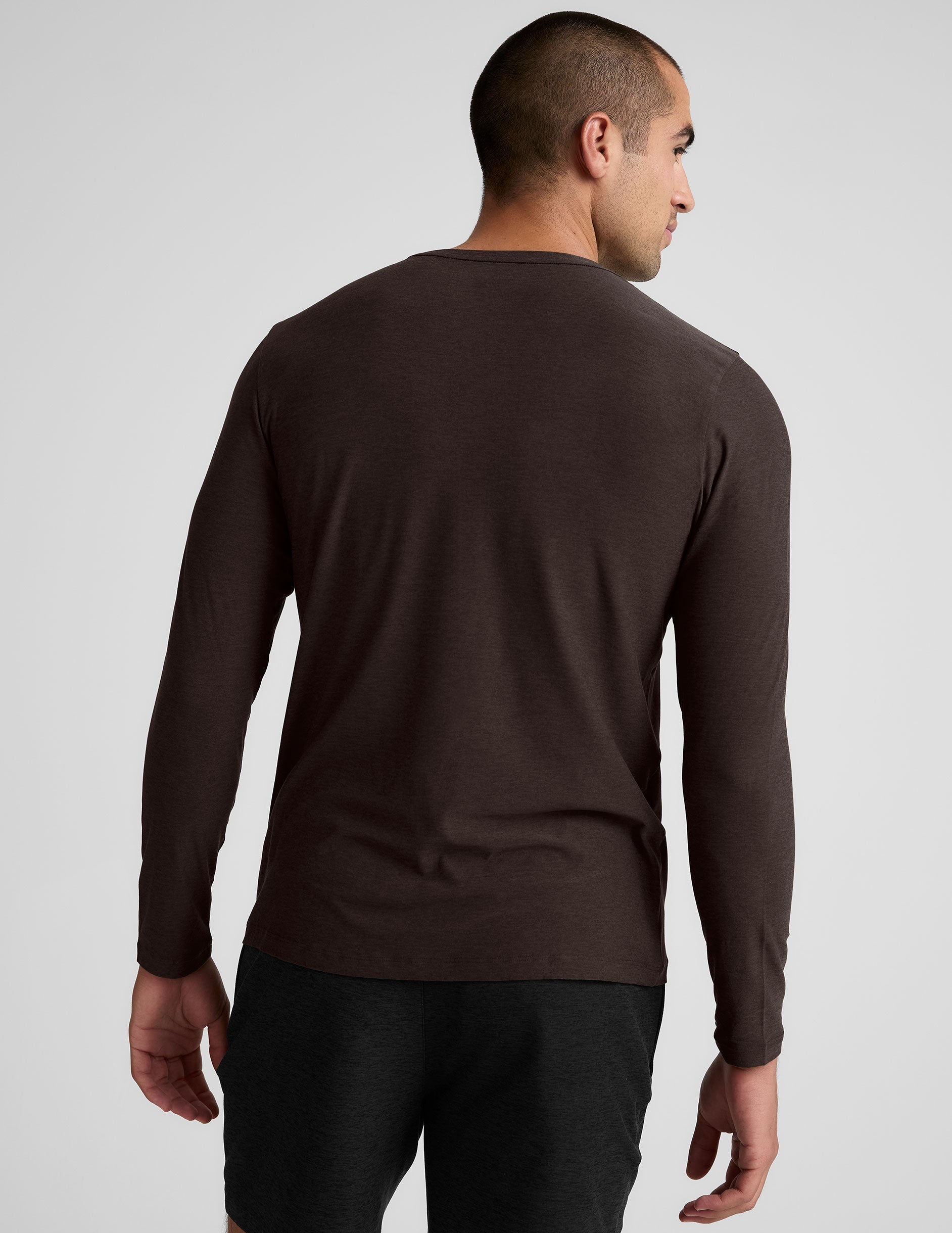 model wearing a brown men's long-sleeve shirt against a gray background.