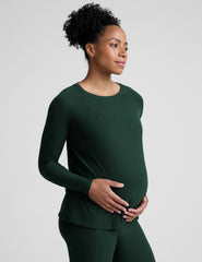 model wearing a green maternity crew neck long-sleeve top and leggings against a light gray background.