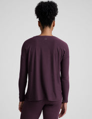 model wearing a purple maternity long sleeve crew neck top and joggers against a light gray background.