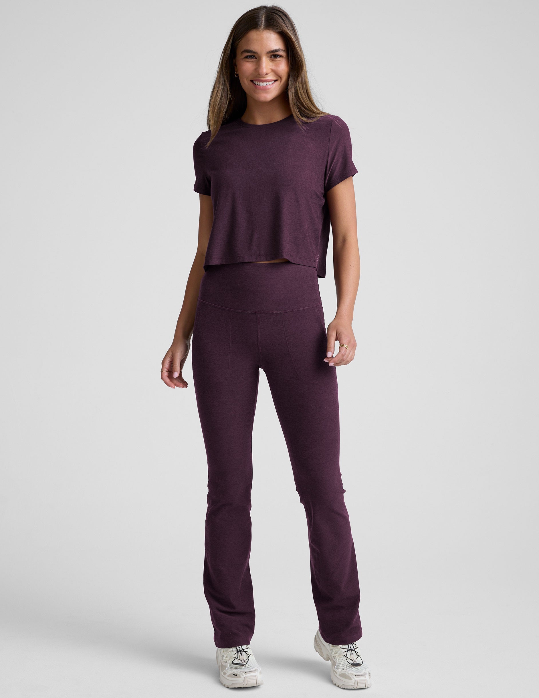 model wearing a purple cropped crew neck t-shirt and pants on a plain background.