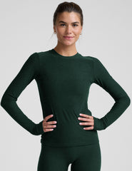 model wearing a green fitted crew neck long-sleeve top against a light gray background.