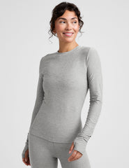 model wearing a fitted gray long-sleeve crew neck top and leggings on a light gray background.