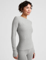 model wearing a fitted gray long-sleeve crew neck top and leggings on a light gray background.