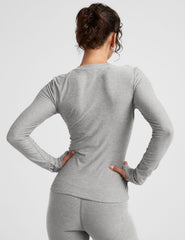 model wearing a fitted gray long-sleeve crew neck top and leggings on a light gray background.