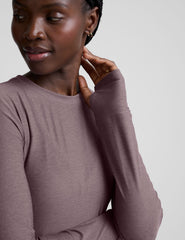 model wearing a mauve long-sleeve fitted crew neck top against a plain background.