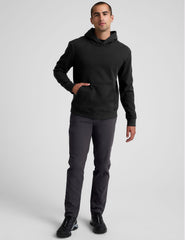 male model wearing a black hoodie and chino pants on a light background.