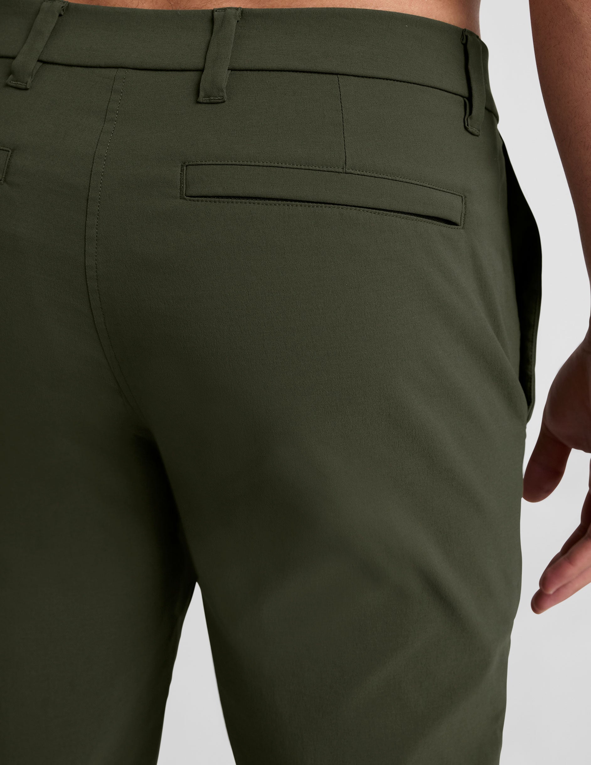 model wearing green men's chino pants on a plain background.