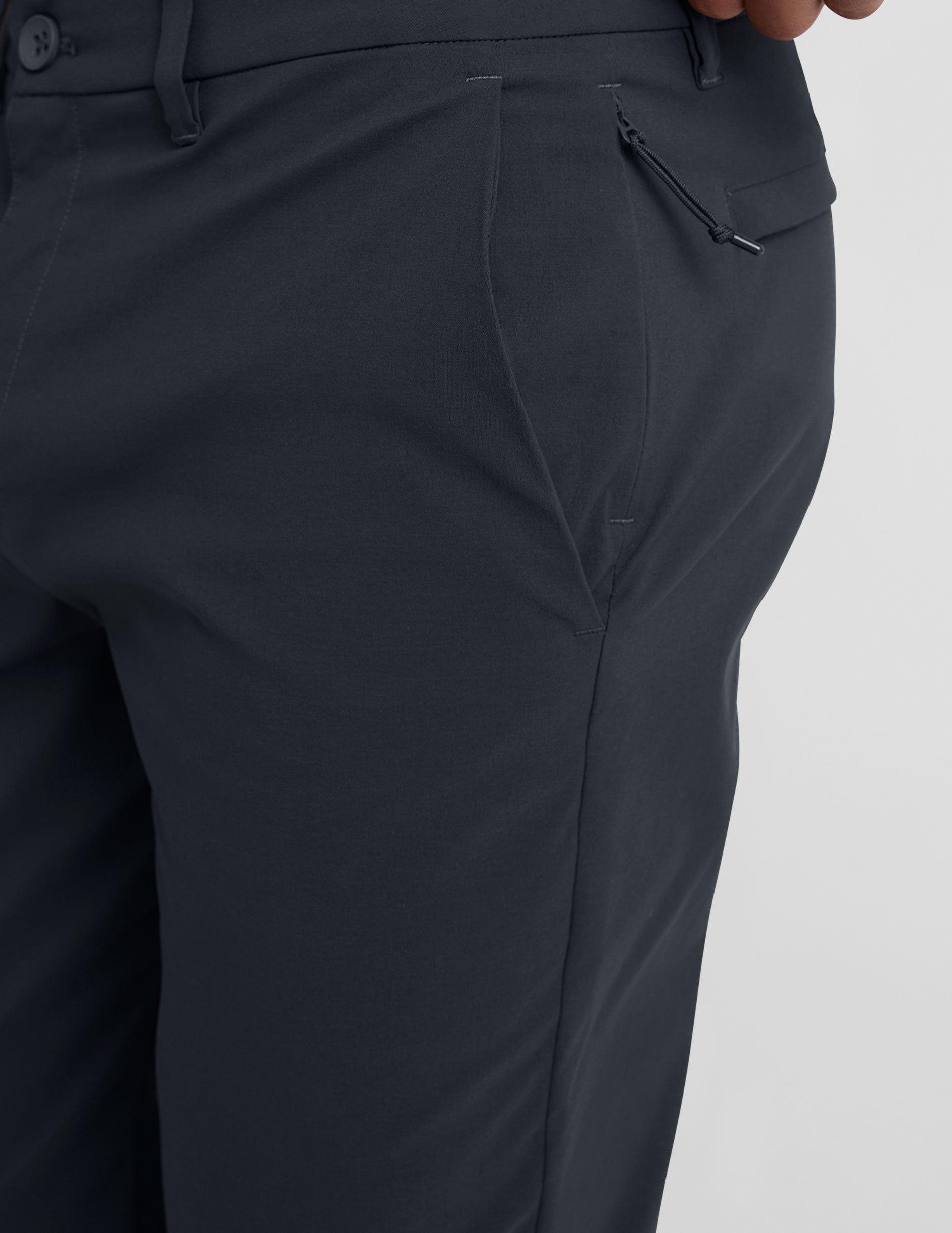 man wearing a gray t-shirt and navy chino pants with pockets against a plain background.