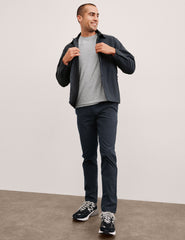 man wearing a gray t-shirt and navy chino pants with pockets against a plain background.