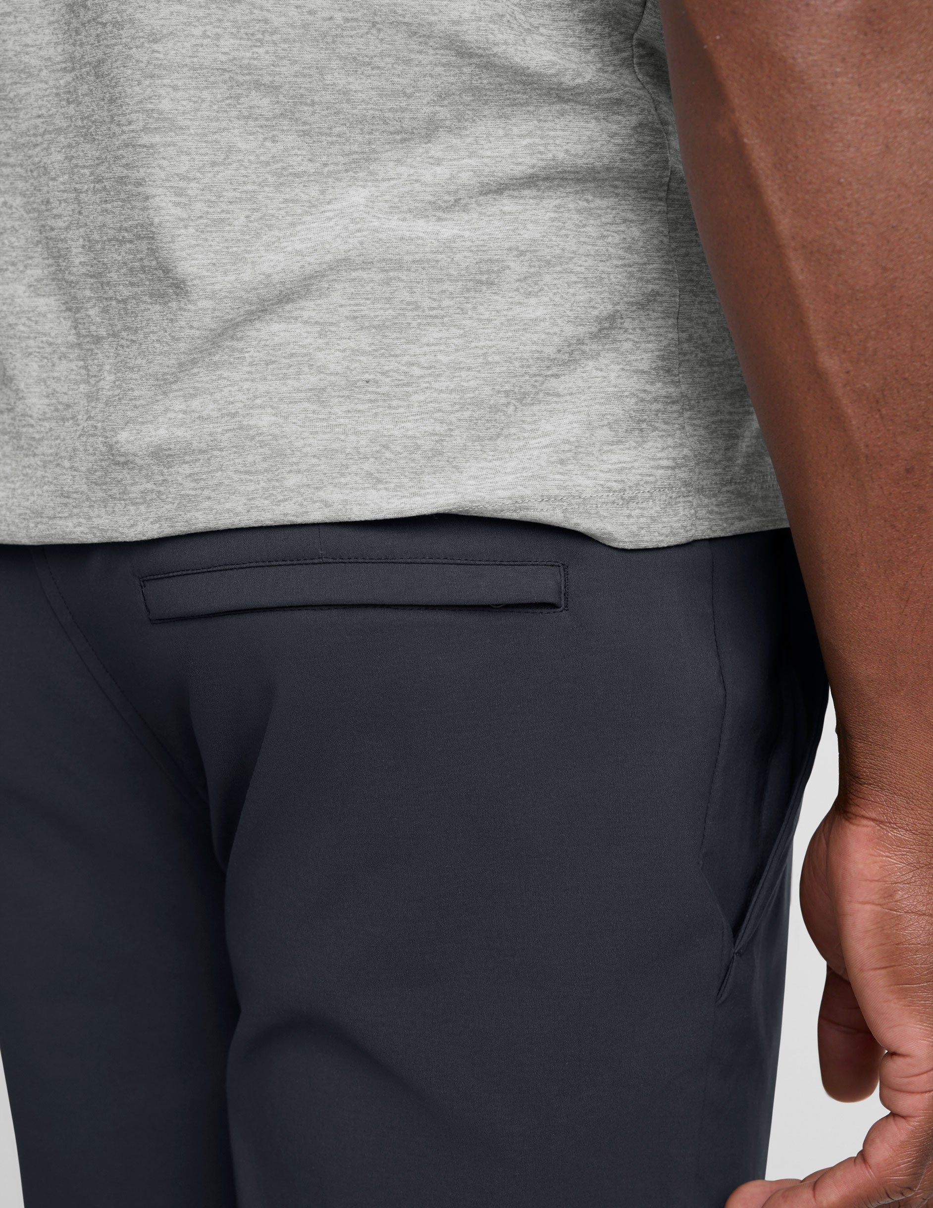 man wearing a gray t-shirt and navy chino pants with pockets against a plain background.