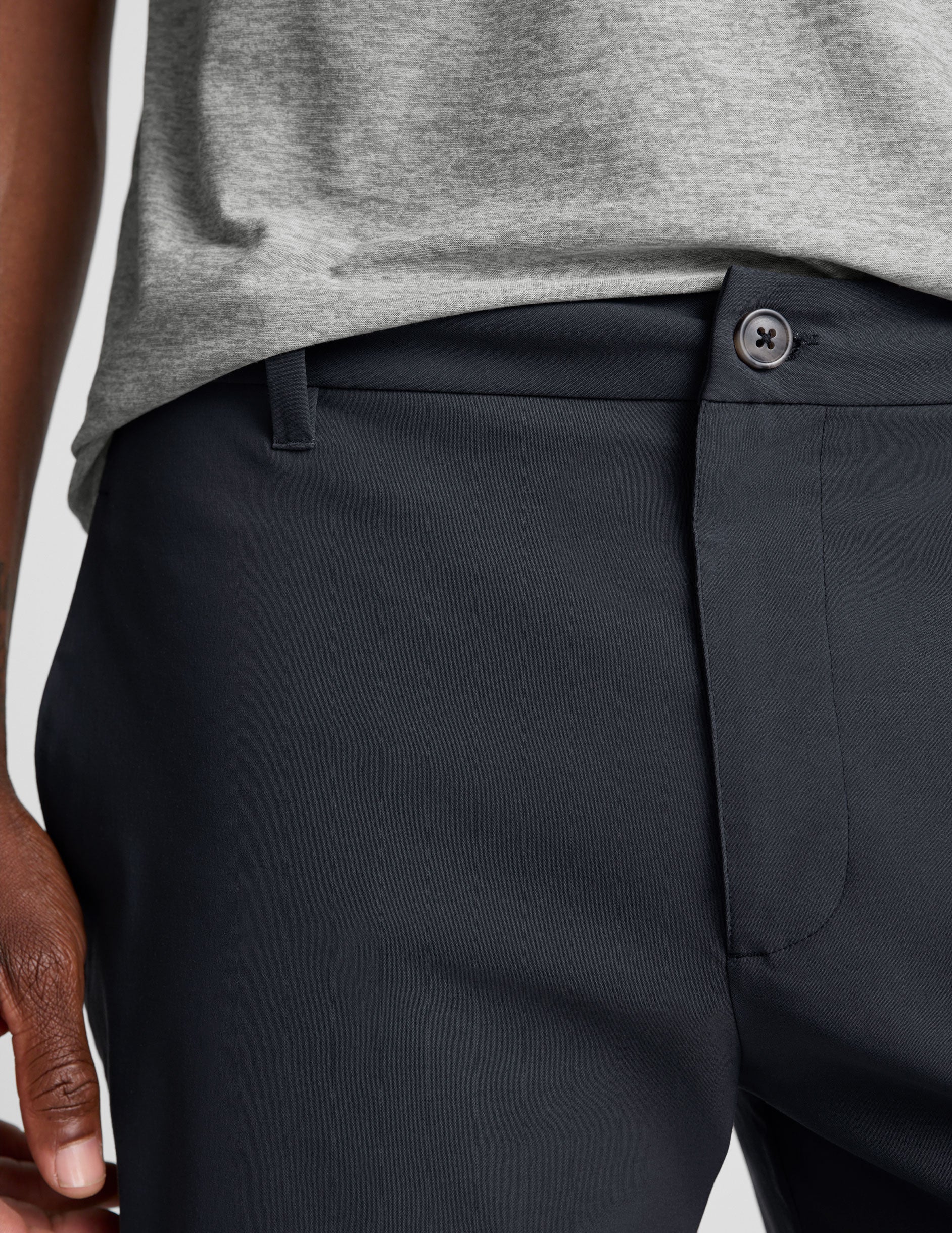 man wearing a gray t-shirt and navy chino pants with pockets against a plain background.