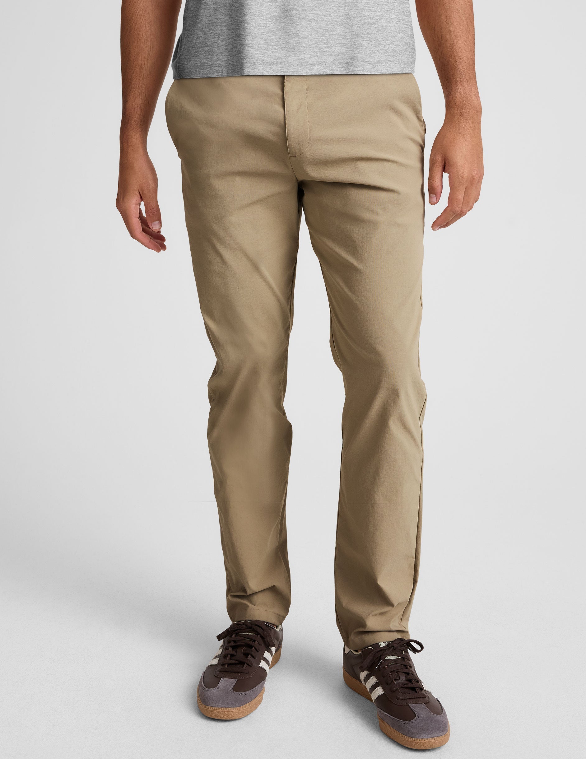 man wearing beige chino pants with side pockets on a plain background.
