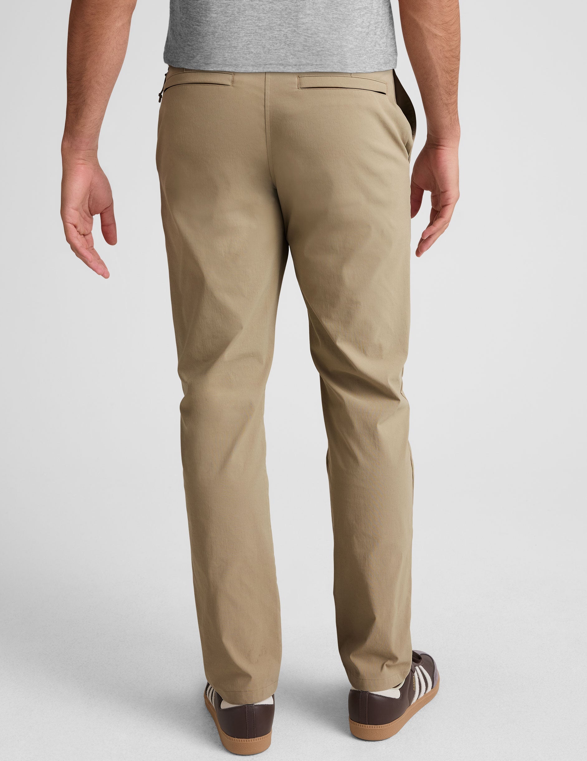 man wearing beige chino pants with side pockets on a plain background.