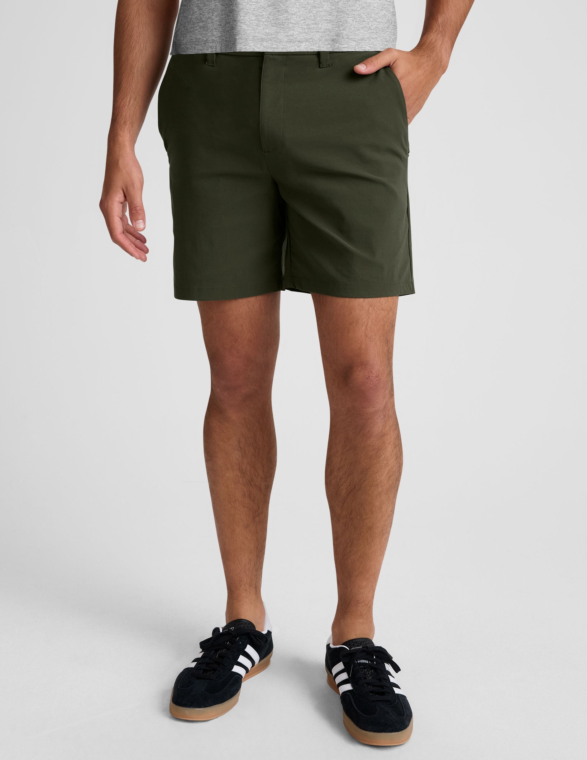 man wearing a grey crew neck t-shirt and green chino shorts with pockets on a plain background.