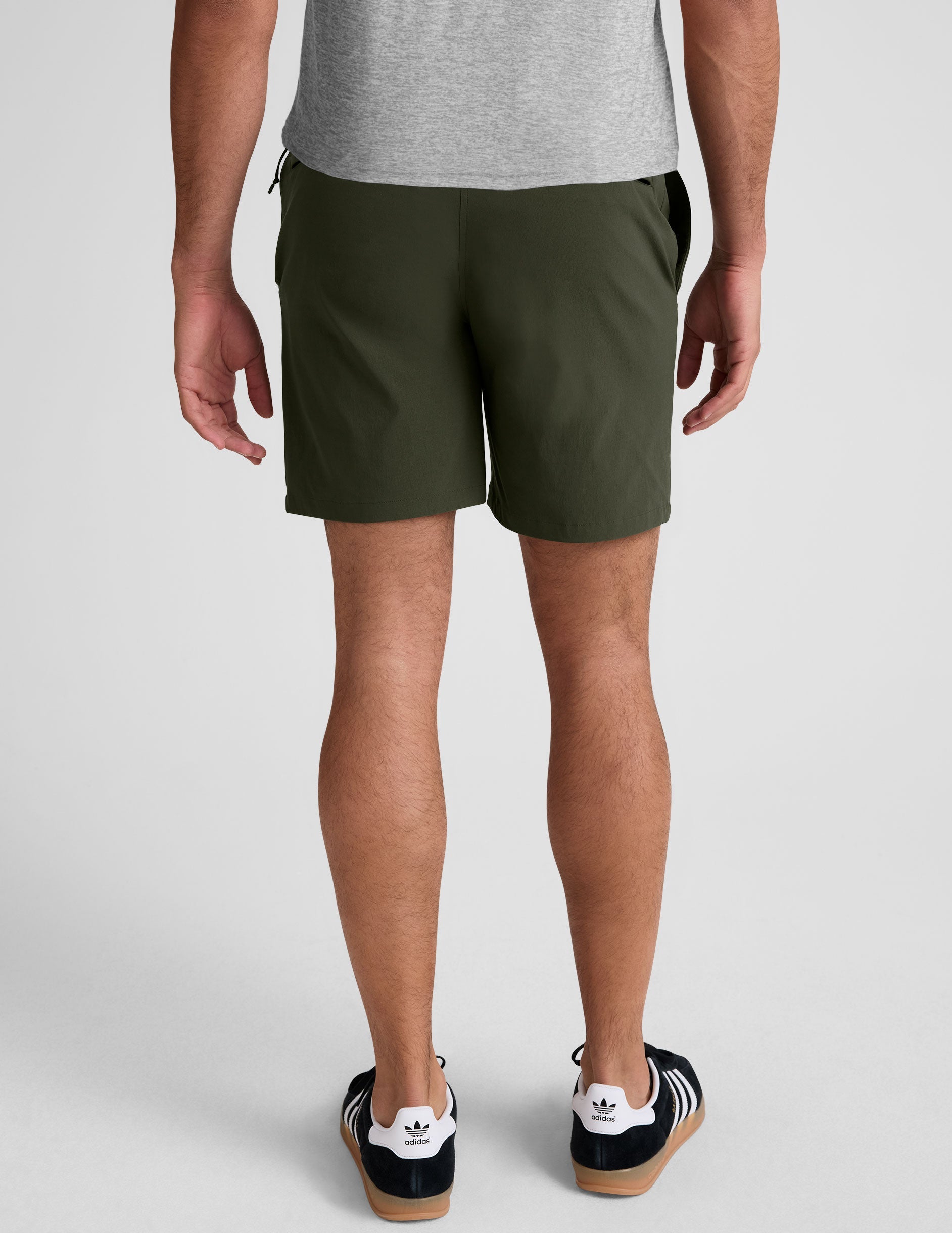 man wearing a grey crew neck t-shirt and green chino shorts with pockets on a plain background.