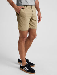 man wearing a grey crew neck t-shirt and beige chino shorts with pockets standing against a plain background.