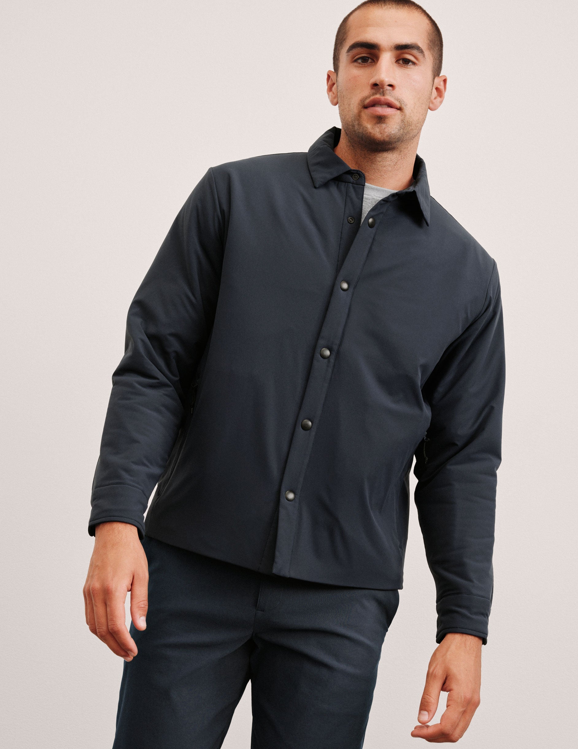 blue men's button up insulated jacket with a shirt collar and side seam invisible zipper pockets.