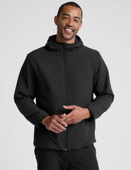 male model wearing a black zip-up jacket with a hood and pockets against a plain background.