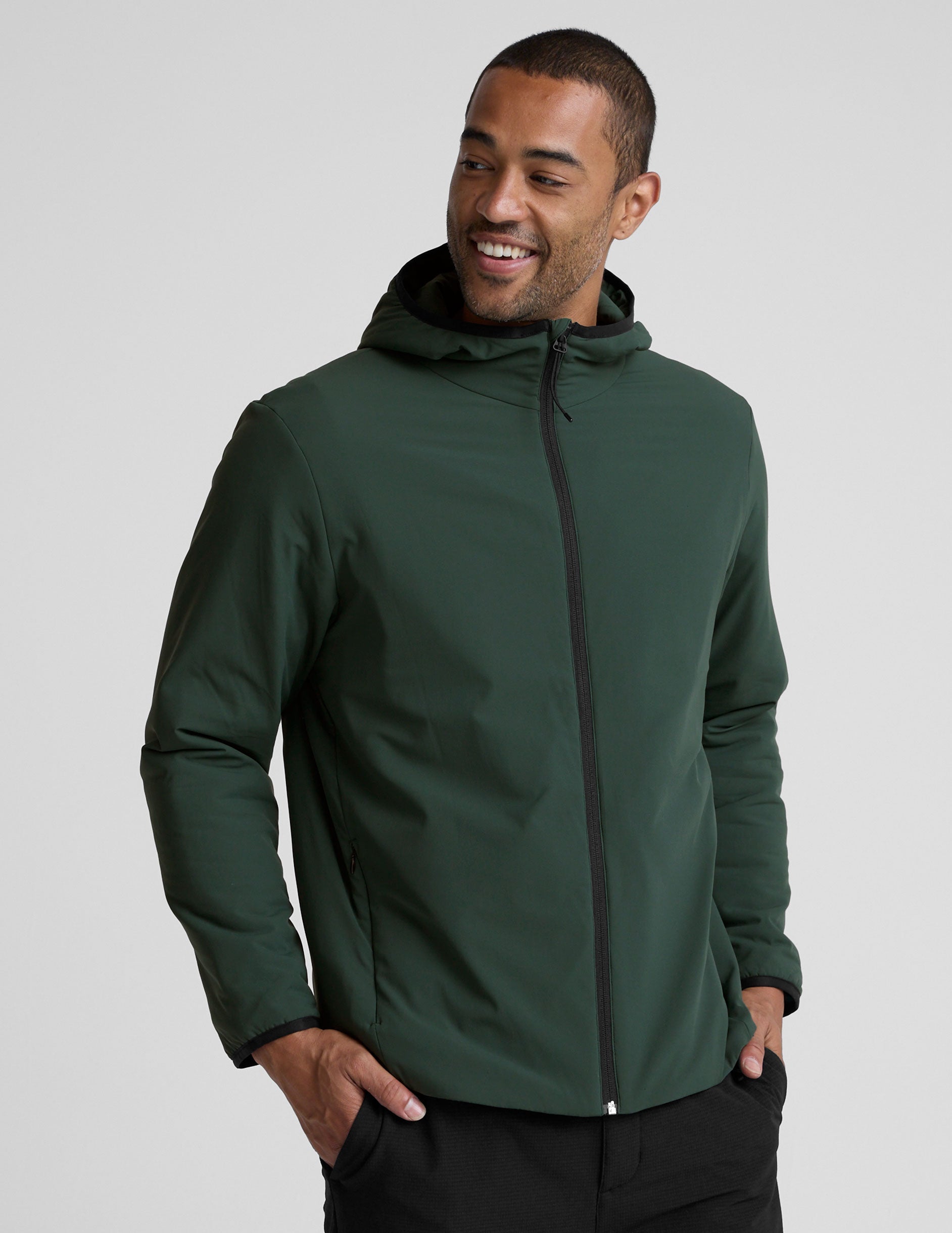 man wearing a green jacket with a hood on a gray background.