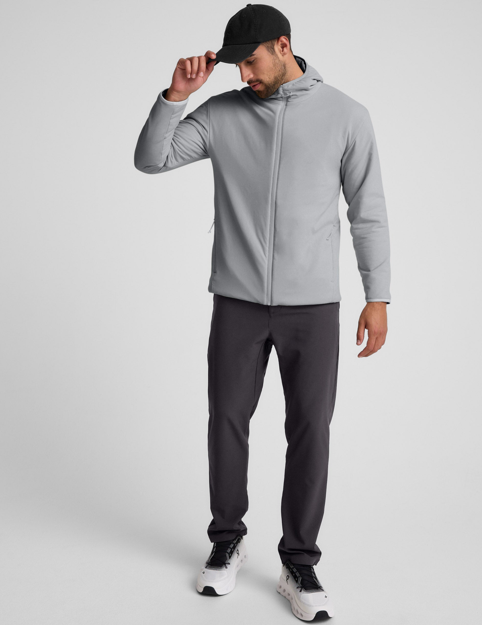 Man wearing a gray jacket and gray pants on a light gray background.