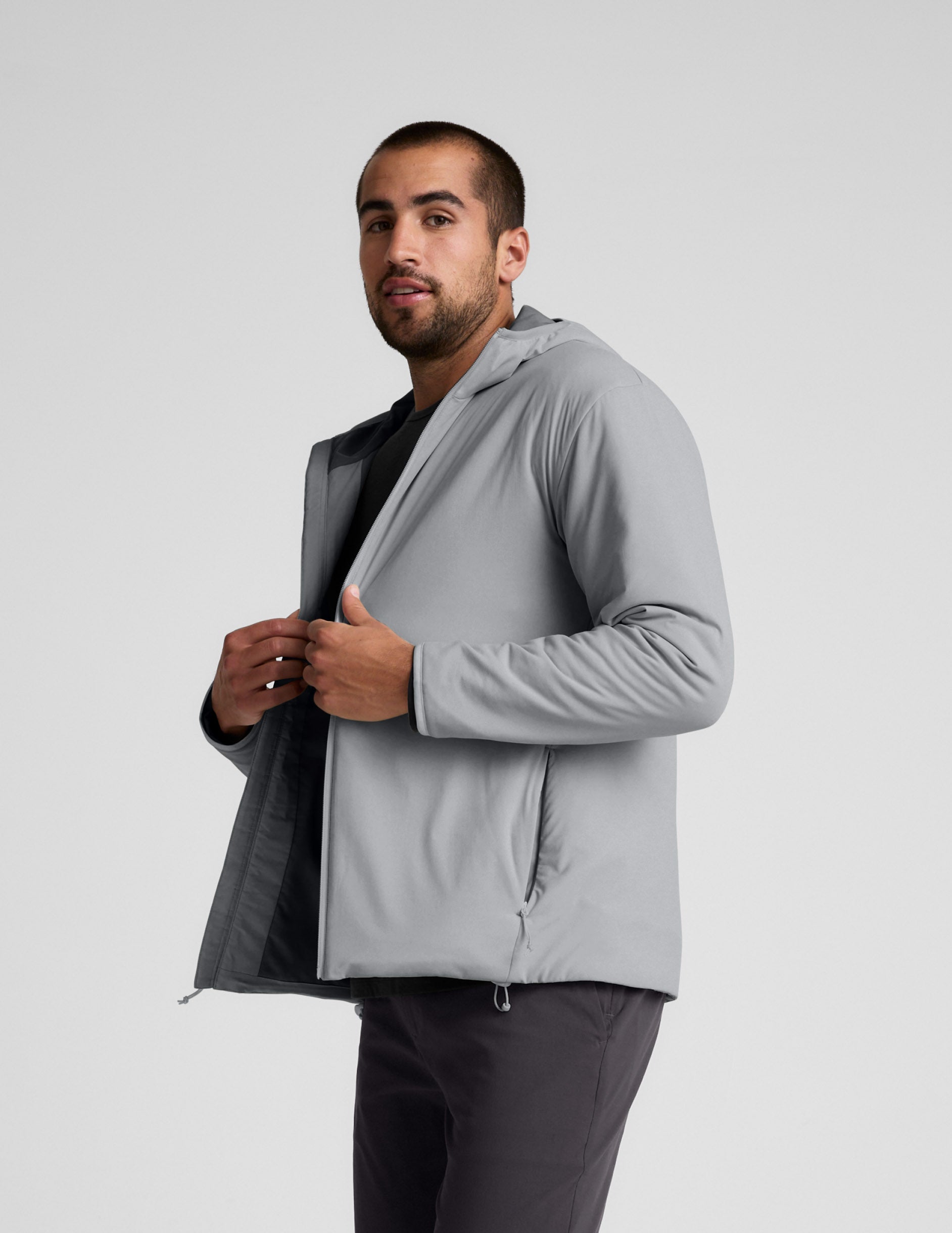 Man wearing a gray jacket and gray pants on a light gray background.