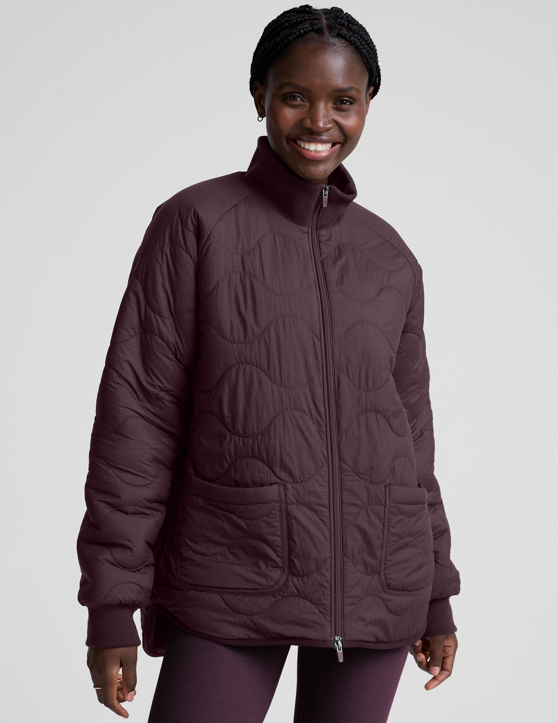 woman wearing a purple quilted jacket against a plain background.