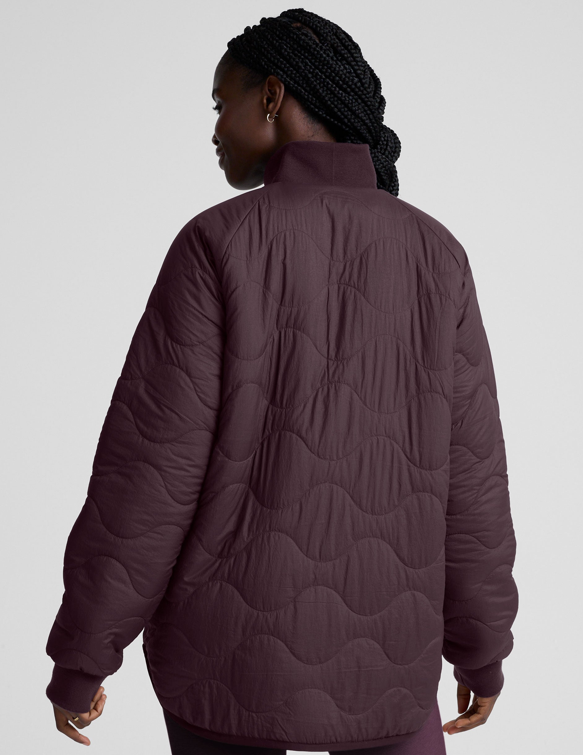 woman wearing a purple quilted jacket against a plain background.