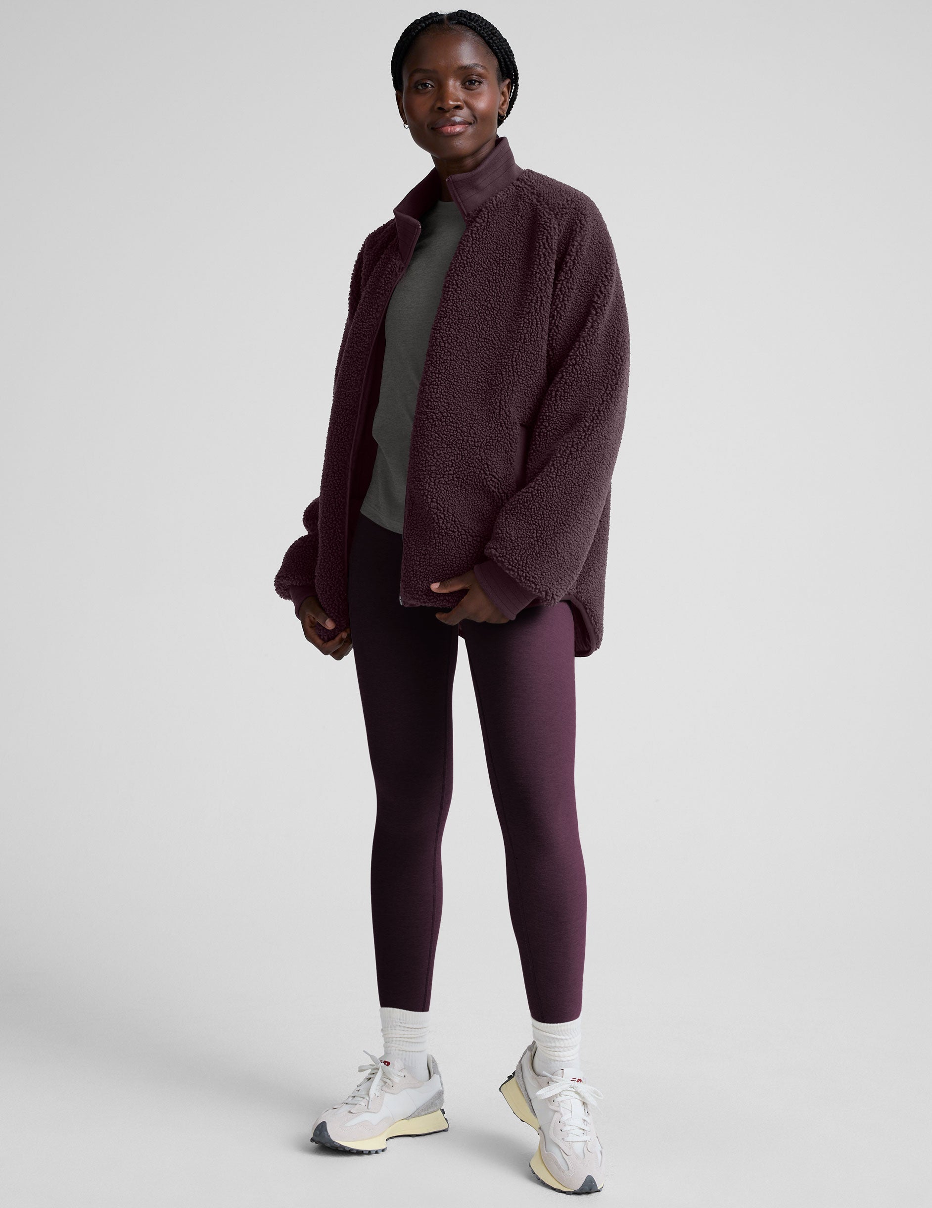 woman wearing a purple quilted jacket against a plain background.