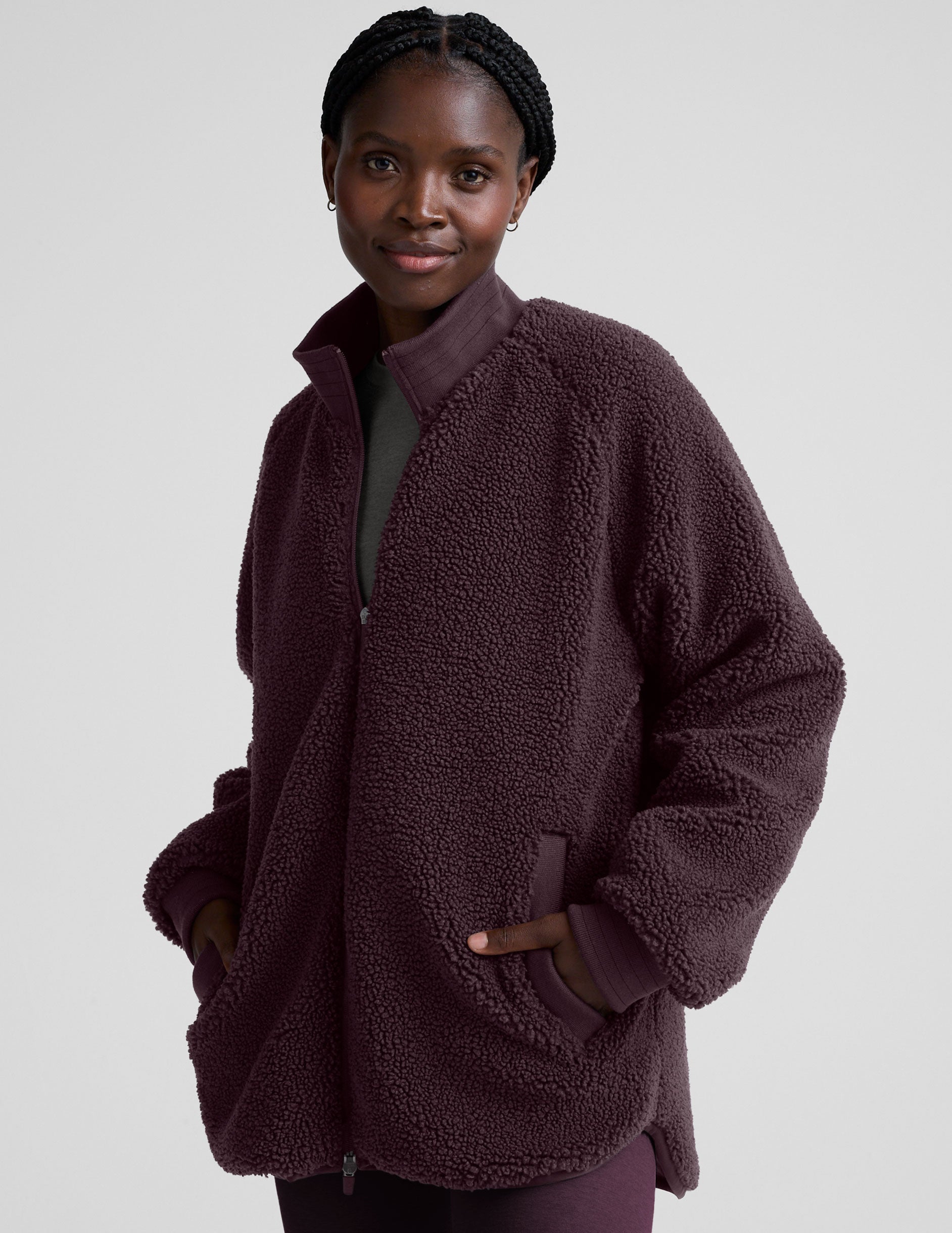 woman wearing a purple quilted jacket against a plain background.