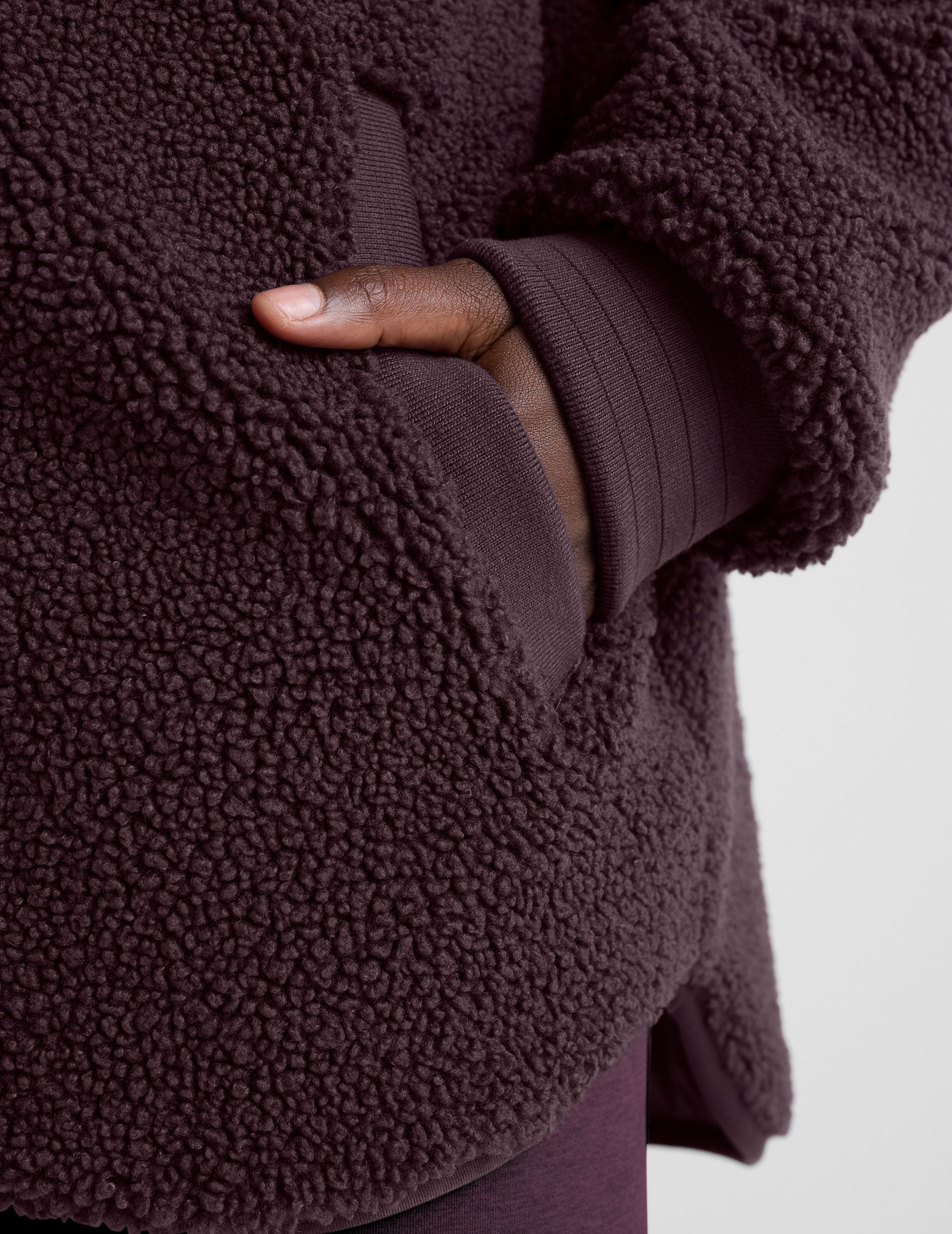 woman wearing a purple quilted jacket against a plain background.