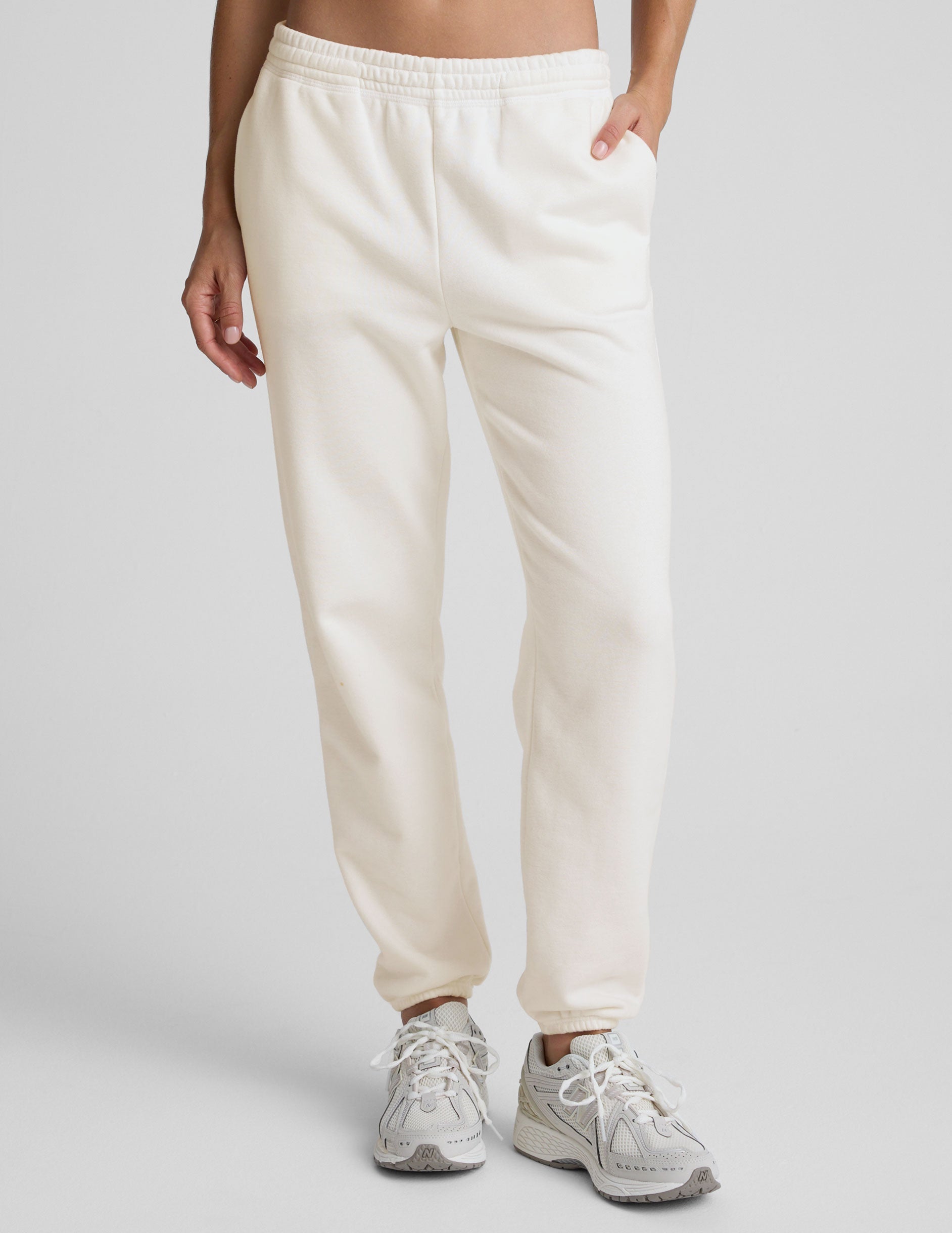 woman wearing white fleece sweatpants against a plain background.