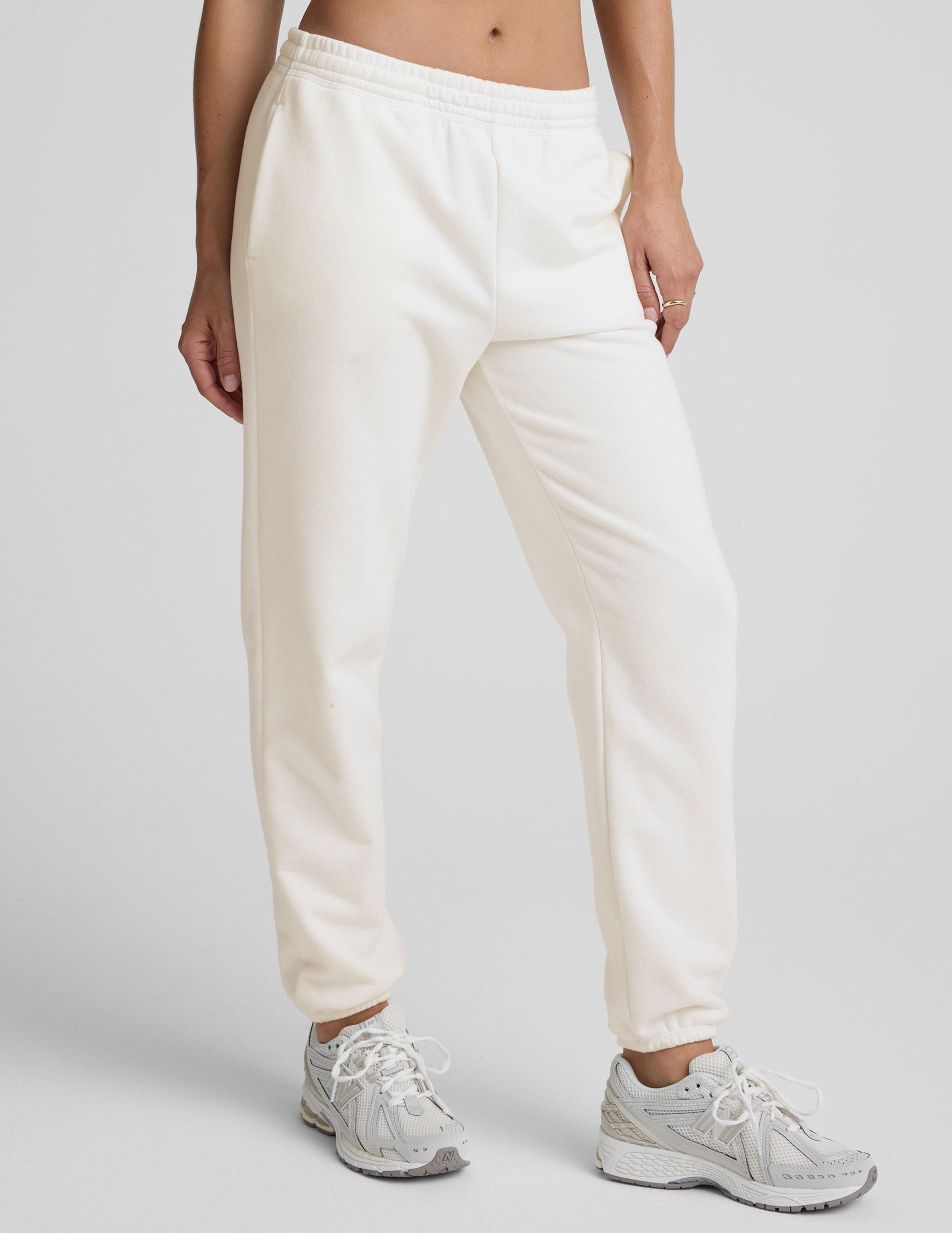 woman wearing white fleece sweatpants against a plain background.
