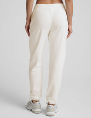 woman wearing white fleece sweatpants against a plain background.