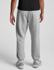 man wearing a black crew neck t-shirt and gray fleece sweatpants on a light gray background.