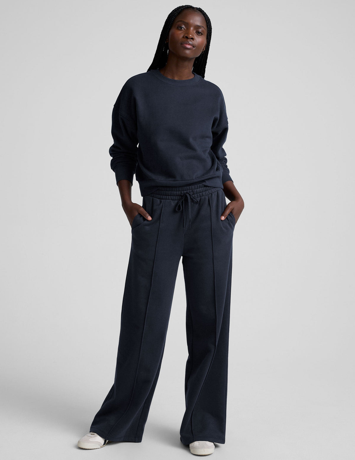 model is wearing a blue crewneck sweatshirt and blue fleece wide leg pants against a plain background.