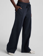 model is wearing blue fleece wide leg pants against a plain background.