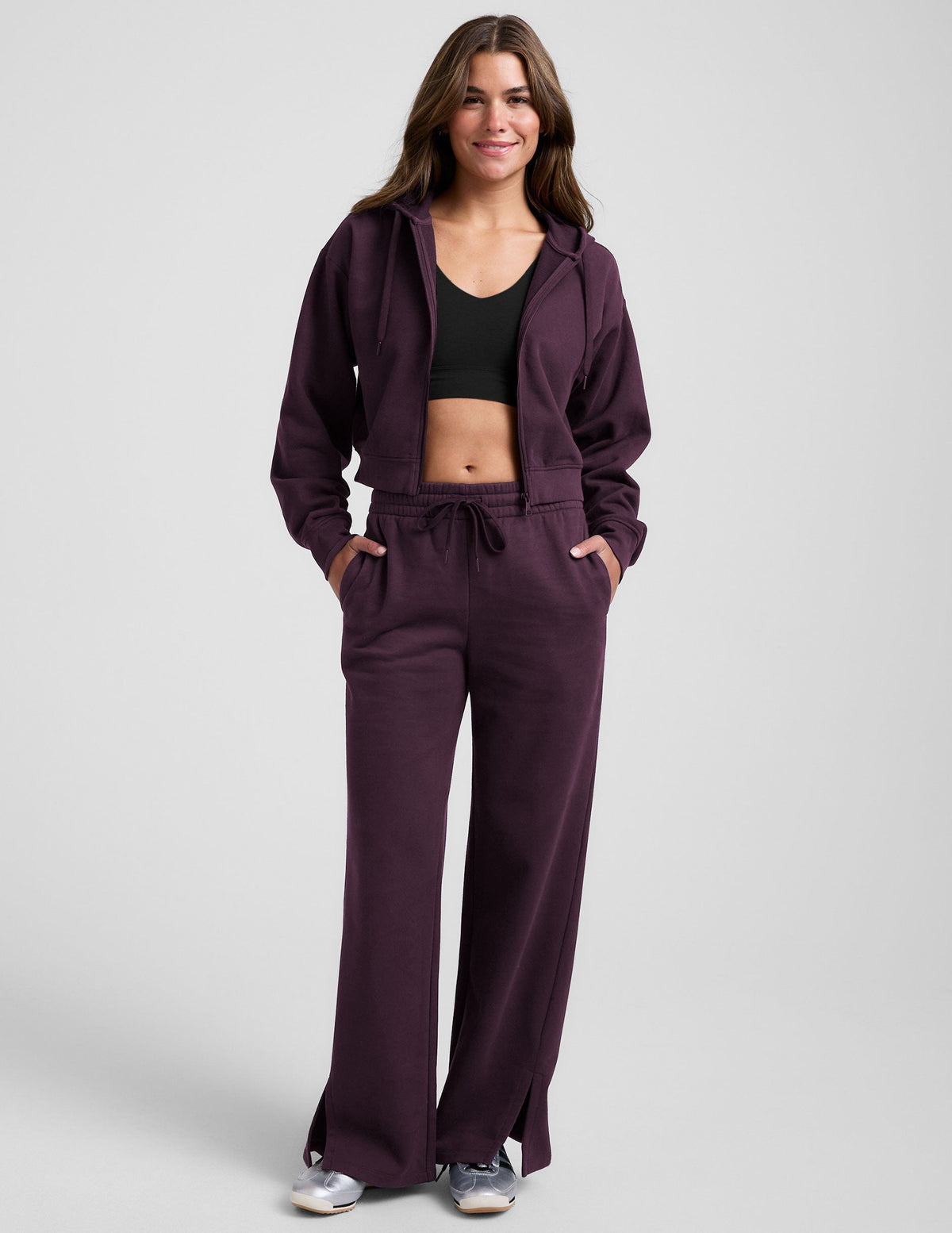 model wearing a purple fleece zip-up jacket and purple fleece wide leg pants with slits on side and a drawcord at waistband on a white background.