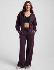 model wearing a purple fleece zip-up jacket and purple fleece wide leg pants with slits on side and a drawcord at waistband on a white background.